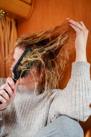 Young Girl Combing Extremely Tangled Hair with Patience and Careの写真素材