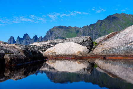 Enchanting Norwegian Fairytale: Serene Sea, Mountains, and Blue Sky Reflection on a Sunny Dayの写真素材