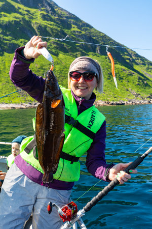 Smiling Woman Fishing in the Norwegian Sea, Holding a Large Catch, Enjoyable Pastime