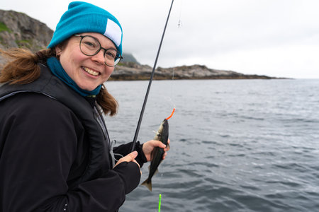 Smiling female fisherman with a big catch in the Norwegian Sea, enjoying her hobbyの写真素材