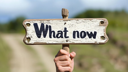 Confused man at crossroad with a  what now  signpost, contemplating uncertain futureの素材