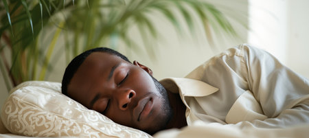 Happy african american man in white clothes sleeping on white bed with copy spaceの素材
