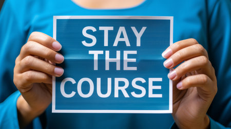 Motivation  woman holding  stay the course  sign on abstract blurred background, success conceptの素材