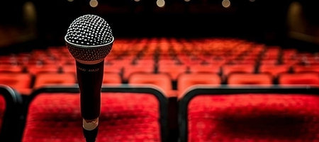 Spotlit microphone on stand in auditorium, live performance concept, copy space for text placement.の素材