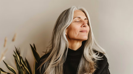 Tranquil middle aged woman meditating at home, relaxing body and mind in living roomの素材