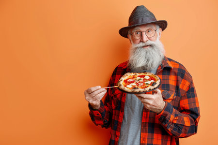 Elderly gentleman enjoying a slice of pizza on soft pastel backdrop, perfect for adding textの素材