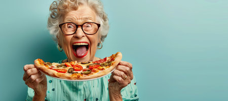 Senior woman savoring pizza on pastel background with ample space for text insertionの素材