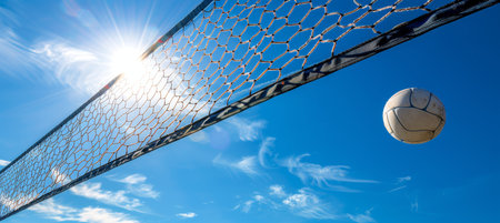 Beach volleyball  ball and net under blue sky, symbolizing summer relaxation and coastal sportsの素材