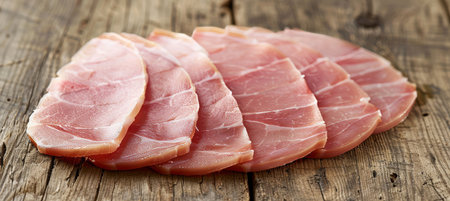 Assortment of delicately sliced cured ham on vintage wooden table for gourmet dining experienceの素材