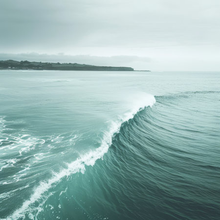 Minimalistic seascape with an ocean wave, cloudy sky, and green coastline, nature backgroundの素材
