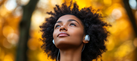 Serene, Beautiful, Young, Black Woman Wearing Headphones And Looking Up On An Autumn, Fall Dayの素材