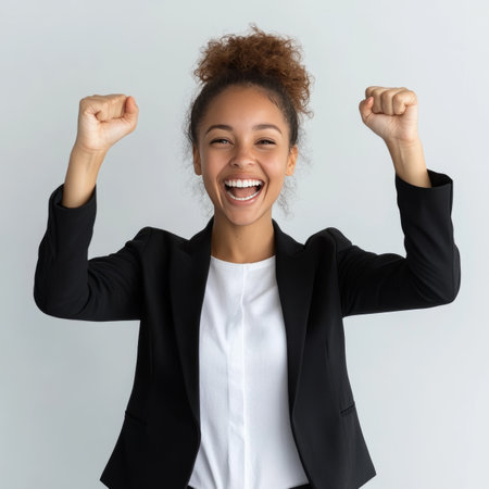 Excited Young Black Businesswoman Celebrating Success with Fists Raised, Isolated on Whiteの素材