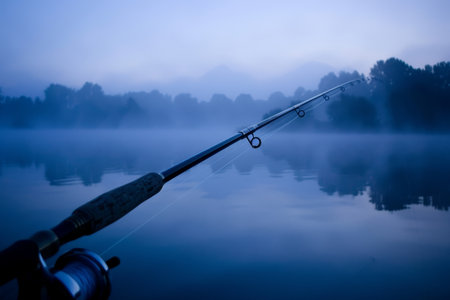 Tranquil Dawn, Fishing Rod and the Misty Lake. Waiting for the Catch on a Serene Morning.の素材