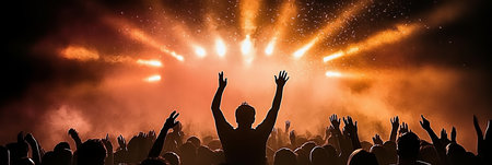 Silhouette of Man with Arms Raised on Stage in Front of Crowd at Concert with Orange Stage Lightsの素材