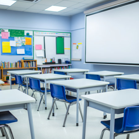 Empty, brightly lit classroom with blue chairs, desks in rows, ready for students to return.の素材