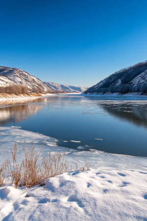 Scenic Winter Landscape, Frozen Lake with Ice Cracks, Blue Sky, and Snow-Covered Hillsの素材