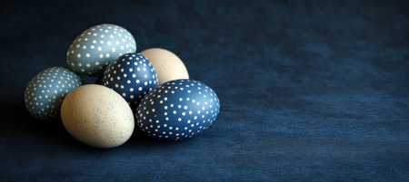 Five Blue And Beige Easter Eggs Decorated With Polka Dot Patterns on Dark Blue Background.の素材