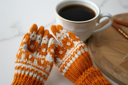Pair of Warm Knitted Mittens with Intricate Design, Cup of Coffee in Blurred Backgroundの素材