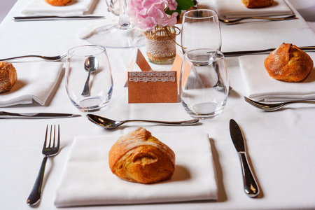 Elegant table setting with bread rolls and pink flowers centerpieceの写真素材