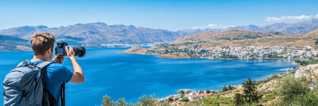 Male Photographer Captures the Beauty of a Coastal Town Nestled by a Tranquil Bay on a Sunny Dayの素材