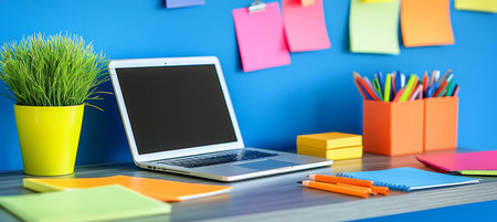 Laptop, notepad, stationery, plant in a pot, color stickers on a blue wall background. Workplaceの素材