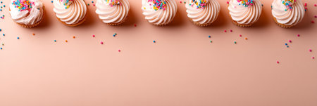 Seven cupcakes in a row on a pink background. Sweet cupcakes decorated with colorful sprinkles.の素材