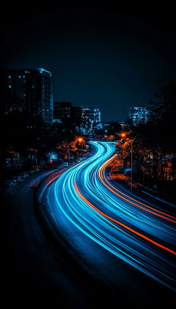 Winding City Road at Night with Long Exposure Light Trails and Blurred Urban Landscapeの素材