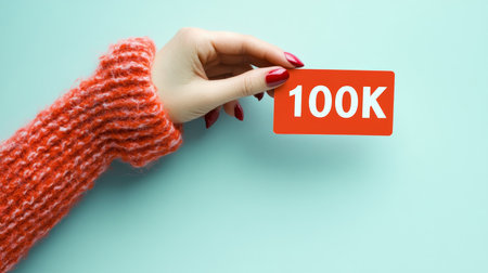 Woman s Hand Holding a Red Card with the Inscription 100k, Celebrating Reaching 100,000 Followers.の素材