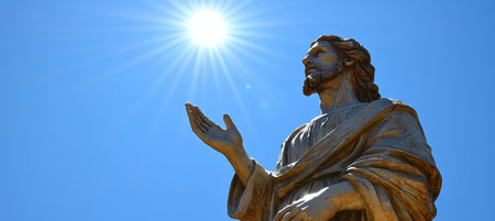 Statue Of Jesus Christ With Outstretched Hand Against Blue Sky, Illuminated by Brilliant Sun Raysの素材