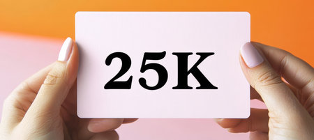 Woman Holds Sign Displaying 25k , Celebrating Milestone Achievement on Vibrant Backgroundの素材