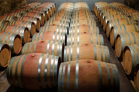 Assorted wooden wine barrels stacked in a rustic wine cellar with dim lighting and rich textures