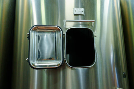 Opened Hatch of a Large Metal Tank or Vat with Shiny Steel Surface and Dark Interior Revealed