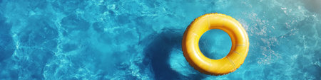 Yellow Inflatable Ring Floating in Glistening Blue Swimming Pool Water, Concept for Summer Vacationの素材