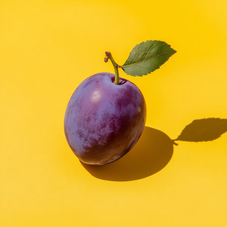 Ripe, vibrant plum with deep purple tones and smooth skin, isolated on a bright yellow background.の素材