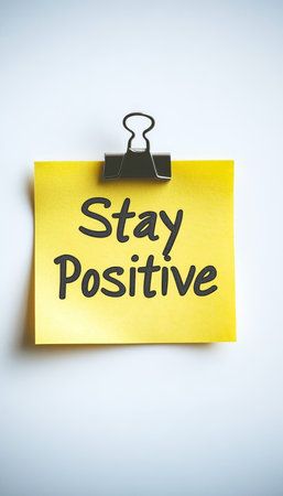 Isolated Yellow Sticky Note Clipped to White Background With Stay Positive, Message.の素材