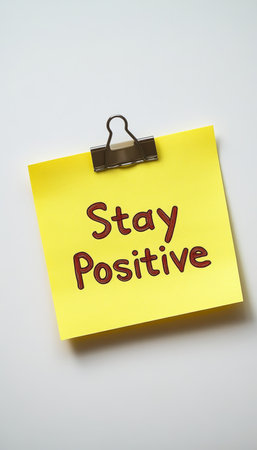 Bright Yellow Sticky Note with Stay Positive Message, Isolated on White Background.の素材