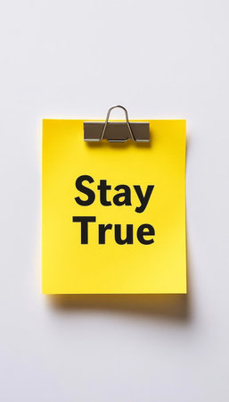Yellow Sticky Note, Isolated On White Background, With The Phrase Stay True Secured By A Black Clip.の素材