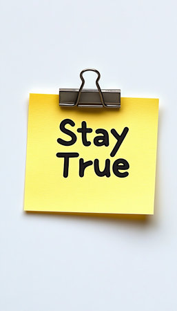 Isolated Yellow Sticky Note With Stay True Message And Binder Clip On White Backgroundの素材