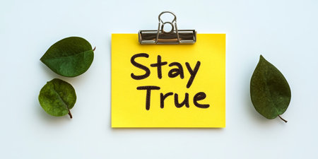 Yellow sticky note with the inscription Stay True and three green leaves for decorationの素材