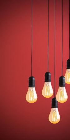 Creative arrangement of illuminated lightbulbs against a bright bold modern red abstract backdropの素材