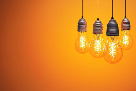 Four Vintage Edison Style Light Bulbs Hanging Against a Bright Orange Background for Creative Usesの素材