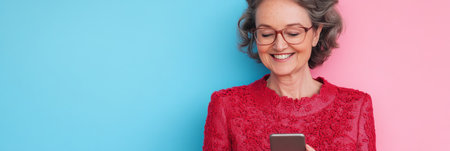 Woman With Glasses Uses Smart Phone Against Blue And Pink Two Toned Banner Backgroundの素材