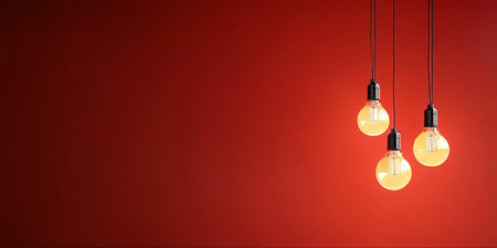 Illuminating Ideas Edison Bulbs Glowing Brightly on Modern Red Backdrop in Minimalist Designの素材