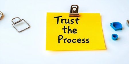 A Yellow Sticky Note Clipped to a Surface Reads Trust the Process Written on It With Clipsの素材