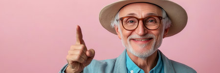 Happy Senior Man in Stylish Hat Smiling and Pointing at Copy Space on Pink Backgroundの素材