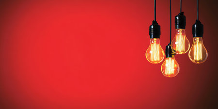 Vintage Glowing Light Bulbs Hanging Against a Warm Red Backdrop for Artistic Home Decor Inspirationの素材