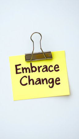 Inspiring yellow sticky note with  embrace change  message on a crisp white backgroundの素材