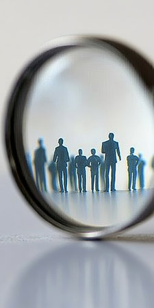Magnifying Glass Focuses on a Single Individual Among a Group, Symbolizing Clarity in Team Dynamicsの素材