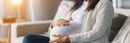 Pregnant Woman Relaxing at Home, Gently Touching Her Round Belly, Embracing the Joy of Motherhoodの素材