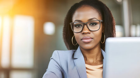 Confident African American Businesswoman Working Diligently on Laptop in Modern Office Environmentの素材